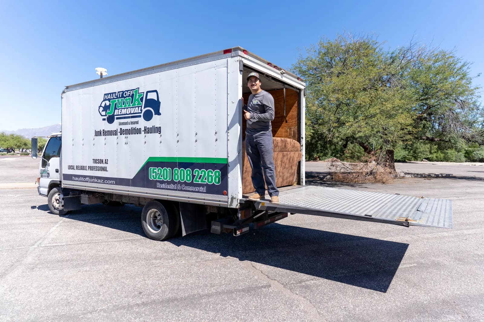 Haul It Off crew member standing in the open truck with a couch loaded and the ramp down